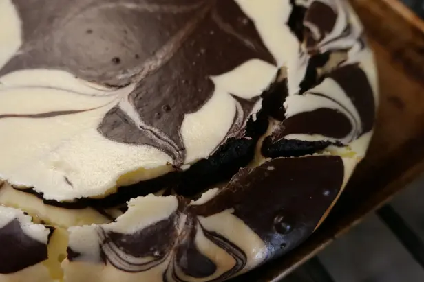 A close-up of a zebra cheesecake with a swirl pattern and cracked filling.